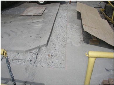 A concrete slab with a yellow handle and some cement.