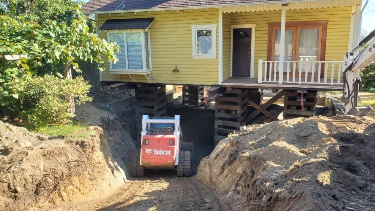 A tractor is parked in the dirt near a house.